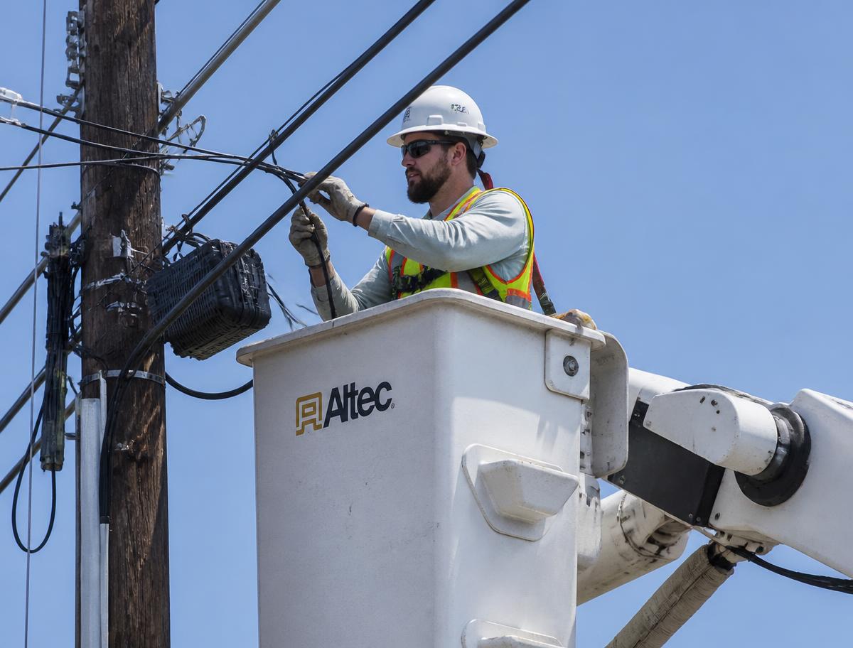 Communications infrastructure technician working with fiber optic and copper cabling in the field