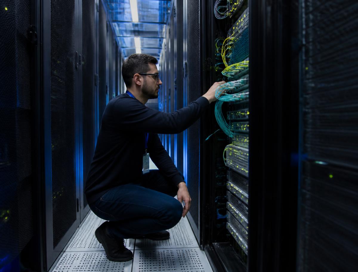 Network infrastructure technician patching switches inside a data center rack